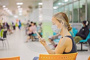 Young woman sitting in hospital waiting for a doctor`s appointment. Patients In Doctors Waiting Room