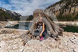 Young Woman Sitting on Huge roots of old trees on Gosausee Vorderer lake