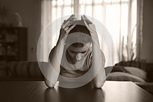 Young woman sitting hugging her head