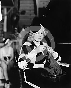 Young woman sitting and knitting at piano