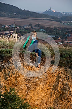 Mladá žena sedí na vápencovej skale pri západe slnka