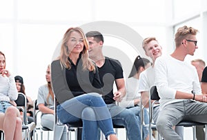 Young woman sitting among the listeners of the business seminar