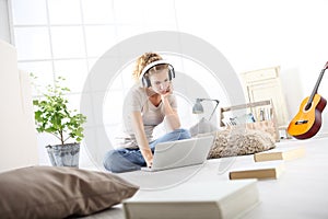 Mujer joven en sala de estar el estudio música auriculares a computadora permanecer sobre el 