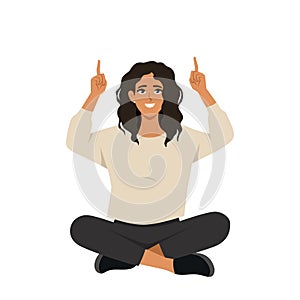 Young woman sitting lotus pose on the floor and pointing index fingers up