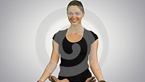 Young woman sitting in lotus yoga pose practicing meditation on white background