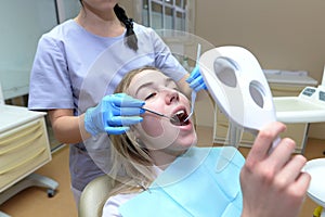 Young woman sitting in a medical chair while a dentist treats her teeth
