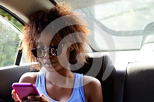 Young woman sitting n backseat of car looking at cell phone