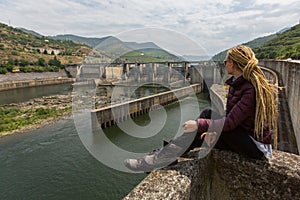 Young woman sitting near an old hydroelectric plant. Walking.