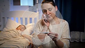 Young woman sitting next to bed of her sick son feeling unwell and talking to doctor. Concept of children illness