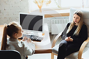 Young woman sitting in office during the job interview with female employee, boss or HR-manager, talking, thinking