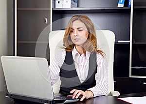 Young woman sitting in office typing on laptop