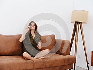 Young woman sitting on an orange couch at home surprise and smile with teeth full, summer, happy vacation home vacations