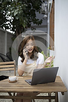 Young woman sitting outdoor cafe and talking on mobile phone.