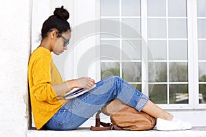 Young woman sitting outdoors and reading a book