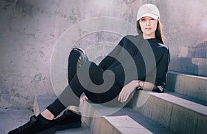 Young woman sitting outside on steps wearing cool fashionable clothing