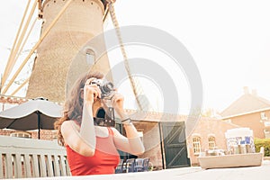 Young woman sitting photographing something in old Dutch mill cafe