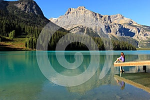 Young woman sitting on a pier at Emerald Lake, Yoho National Par