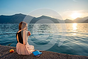 Young woman sitting on the pier at sunrise