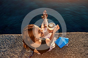 Young woman sitting on the pier at sunrise