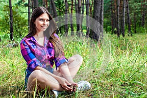Young woman sitting in a pine tree forest