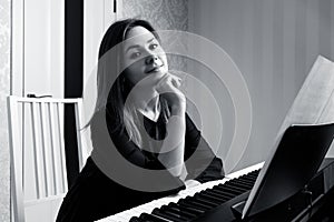 Young woman sitting and playing on the electronic piano