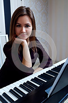 Young woman sitting and playing on the electronic piano