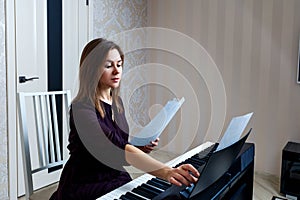 Young woman sitting and playing on the electronic piano