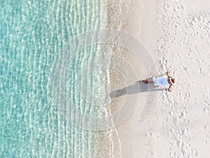 Young woman sitting and relaxing at beautiful tropical white sand beach with wave foam and transparent sea, Summer vacation and