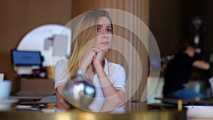 Young woman sitting in restaurant alone tapping on smartphone waiting for a date. Upset pretty Caucasian blonde female