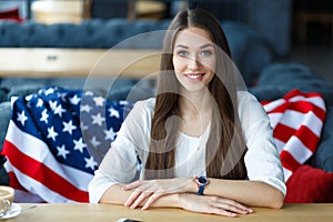 Young woman sitting in the restaurant. American flag behin