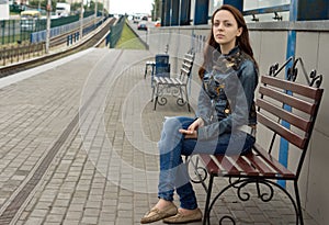 Young woman sitting on a roadside bench