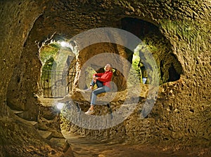 Young woman sitting on the rock .Derinkuyu cave underground city photo