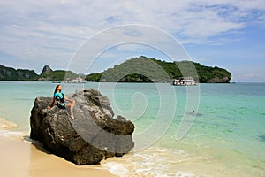 Young woman sitting on a rock at Wua Talab island, Ang Thong Nat