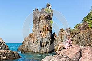 Young woman sitting on rocks sea coast.