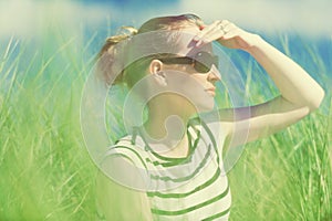 Young woman sitting in sand dunes amongst tall grass relaxing, enjoying the view on sunny day