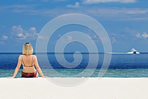 Young woman sitting at the sea shore.