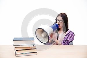 Young woman sitting and shouting in megaphone