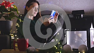 Young woman sitting on the sofa in Christmas decorated living room using mobile phone.