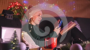 Young woman sitting on the sofa in Christmas decorated living room using mobile phone.