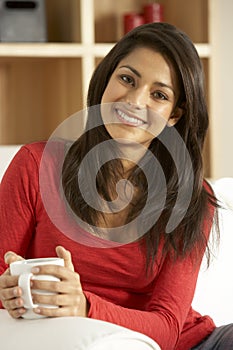 Young Woman Sitting On Sofa With Cup Of Coffee