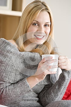 Young Woman Sitting On Sofa With Cup Of Coffee
