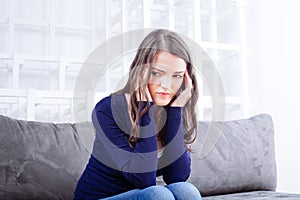 Young Woman Sitting On Sofa having headache migraine