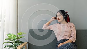 Young woman sitting on the sofa listening to music chilling and smiling relax