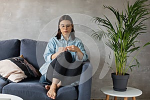 A young Woman is Sitting on the Sofa Looking at the Camera. The Girl Is Worried, Sad. Depression.