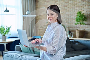 Young woman sitting on sofa using laptop for work, freelancing, learning