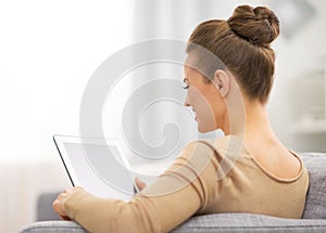 Young woman sitting on sofa and using tablet pc