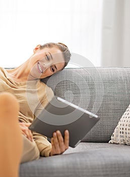 Young woman sitting on sofa and using tablet pc