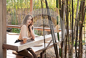 Young woman sitting in a summer cafe with a cocktail and look at camera