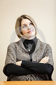 Young woman sitting at table with hands clasped