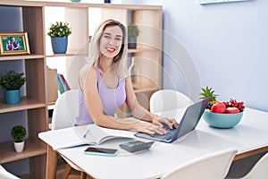 Young woman sitting on table teleworking at home